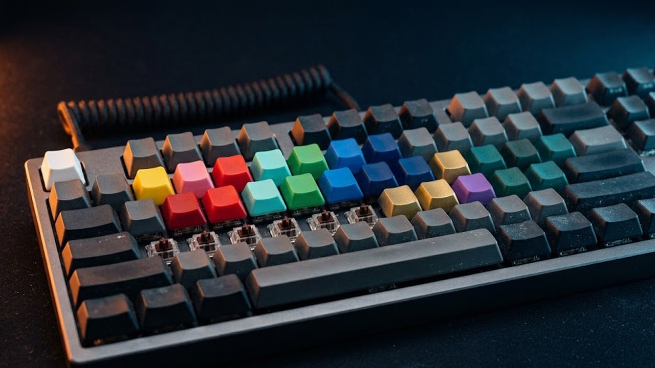 Close-up of a dark mechanical keyboard with sixteen keycaps in sixteen different colours